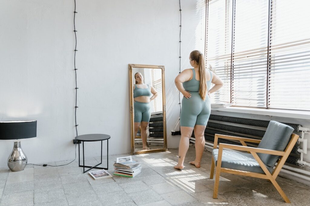 An obese woman standing in front of a mirror
