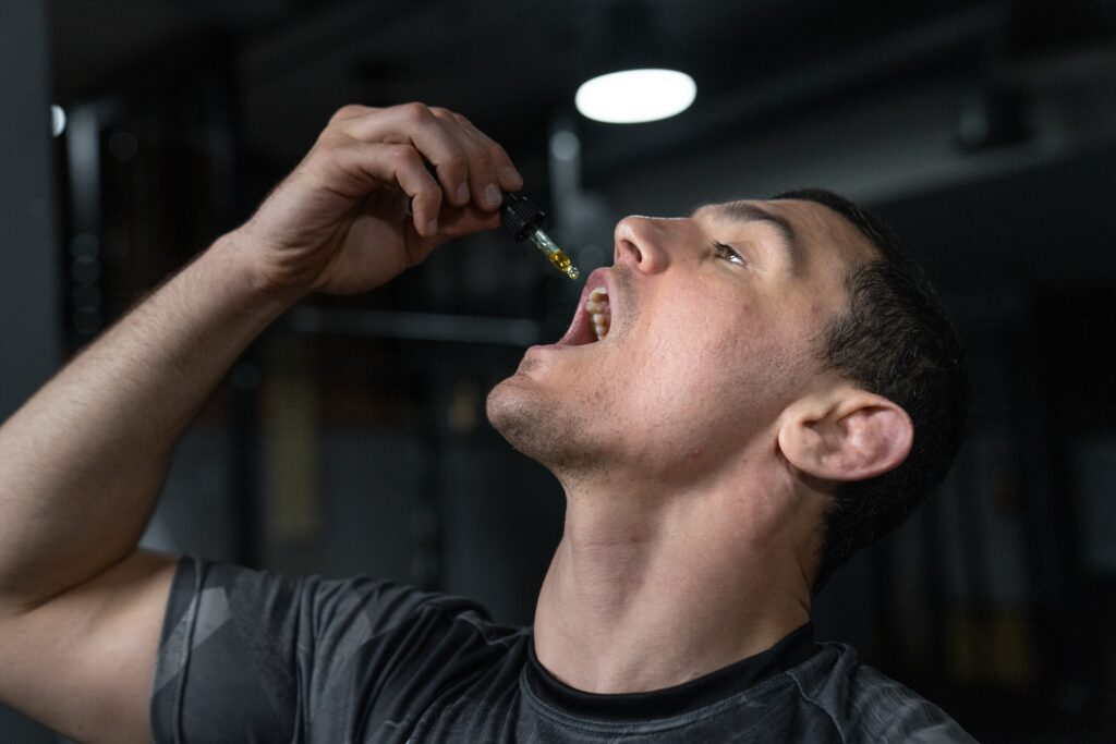 A man holds a dropper of oil above his mouth