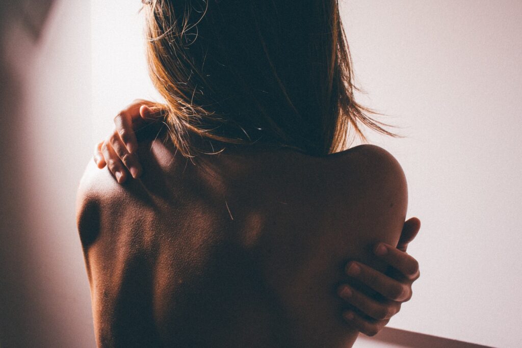 a woman rubbing her shoulders and back due to pain from muscle spasms